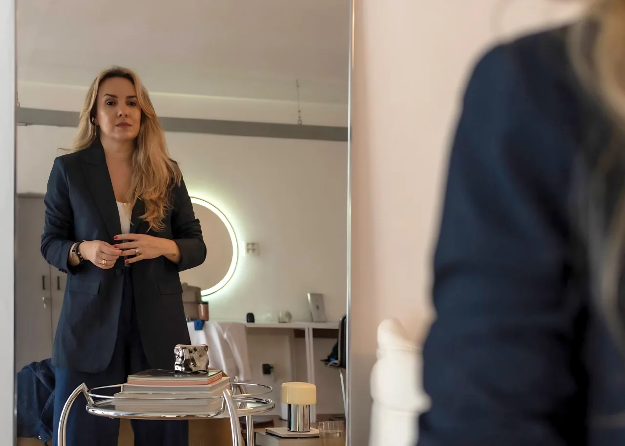 Débora Bolangno refletida no espelho com postura profissional